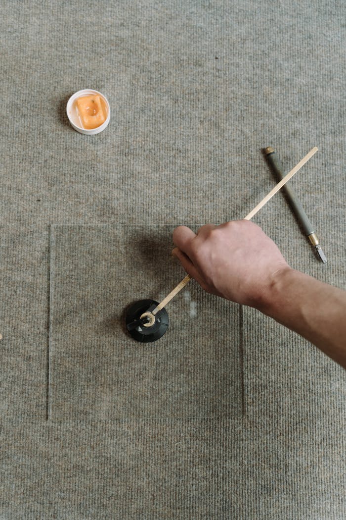 A craftsman uses a specialized tool for precision glass cutting, showcasing skill and craftsmanship.